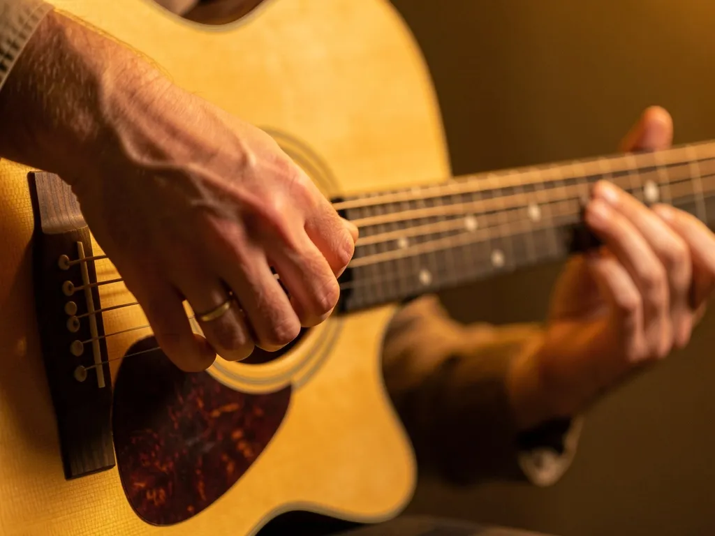 Mão direita de violonista executando padrão de arpejo não convencional no violão